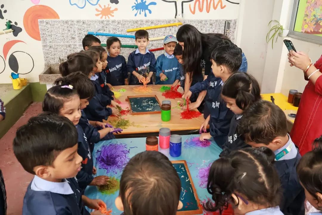 A class gathered around a table of paint trays during a messy play session