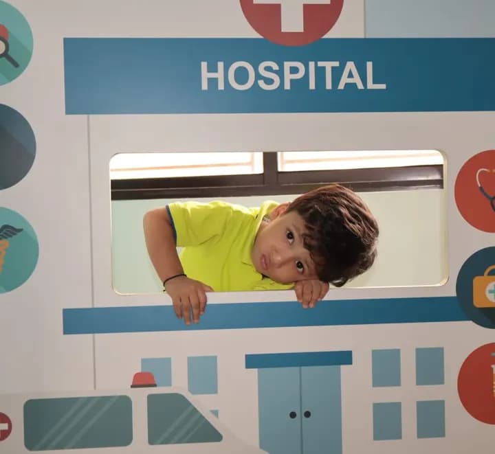 A child at the window of the hospital role play unit in the Explorers' Den