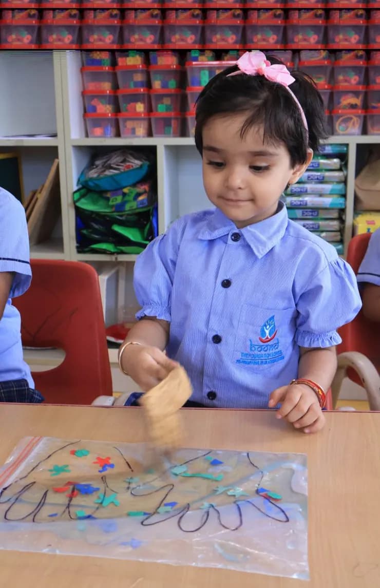 A child painting a textured artwork at her desk