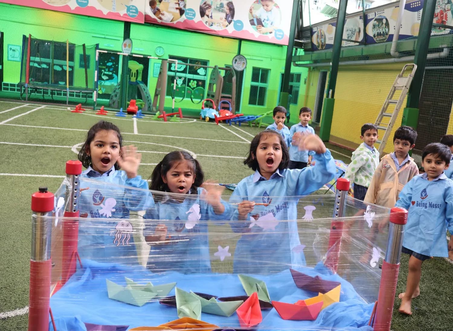 Children cheering at paper boats floating in a water tray